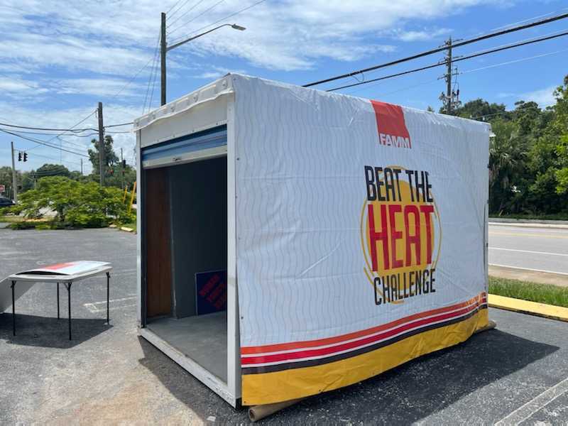 A metal pod sits in a parking lot on a sunny day. The pod reads 